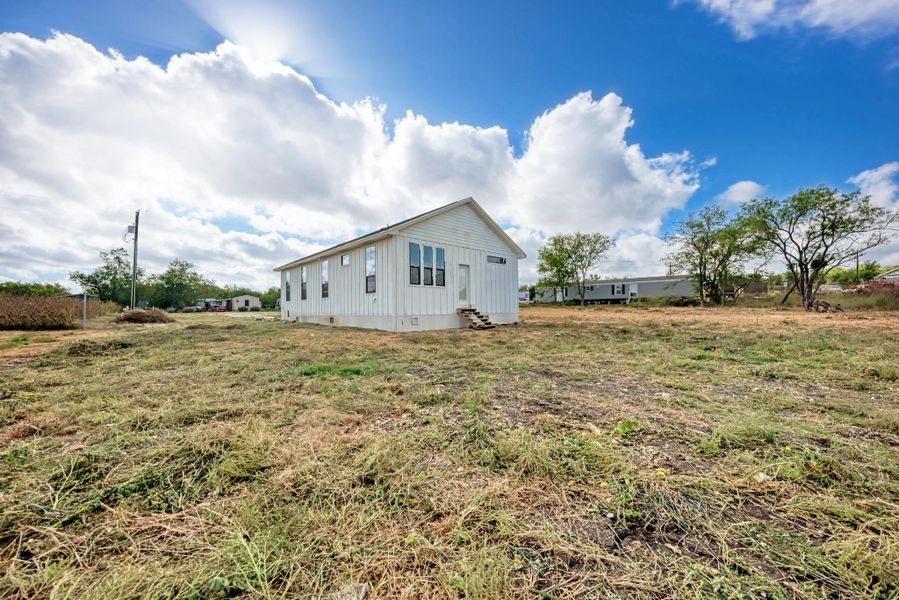 Board and batten siding defines this modern single-story home set on a grassy lot.