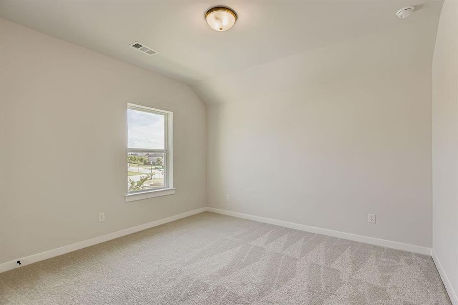 Empty room featuring light colored carpet, a smoke detector, and lofted ceiling