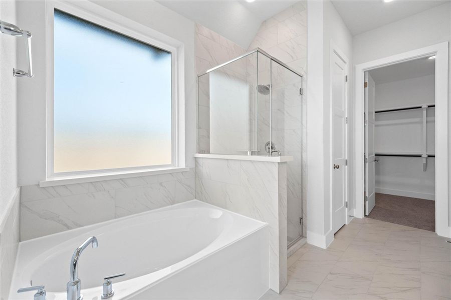 This alternate view of the primary bathroom showcases a walk-in shower with a stylish tile surround, a separate garden tub perfect for unwinding after a long day, and a large rain glass window that provides natural light while maintaining privacy.