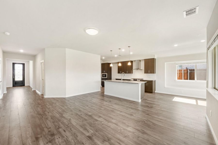 Open-concept living area with kitchen island, dark wood cabinets, and hardwood floors