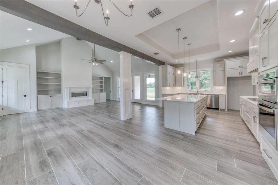 Kitchen featuring light wood-type flooring, hanging light fixtures, white cabinets, lofted ceiling, and a center island