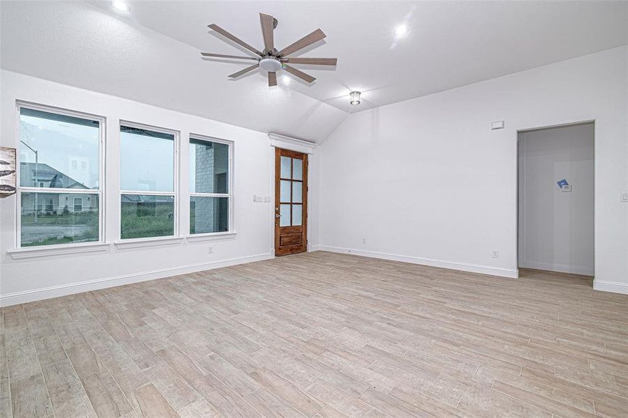 Empty room with vaulted ceiling, a ceiling fan, light wood finished floors, baseboards, and recessed lighting Empty room with vaulted ceiling, a ceiling fan, light wood finished floors, baseboards, and recessed lighting