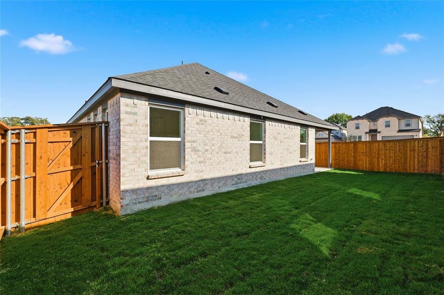 Back of house with brick siding, a fenced backyard, a shingled roof, and a gate Back of house with brick siding, a fenced backyard, a shingled roof, and a gate