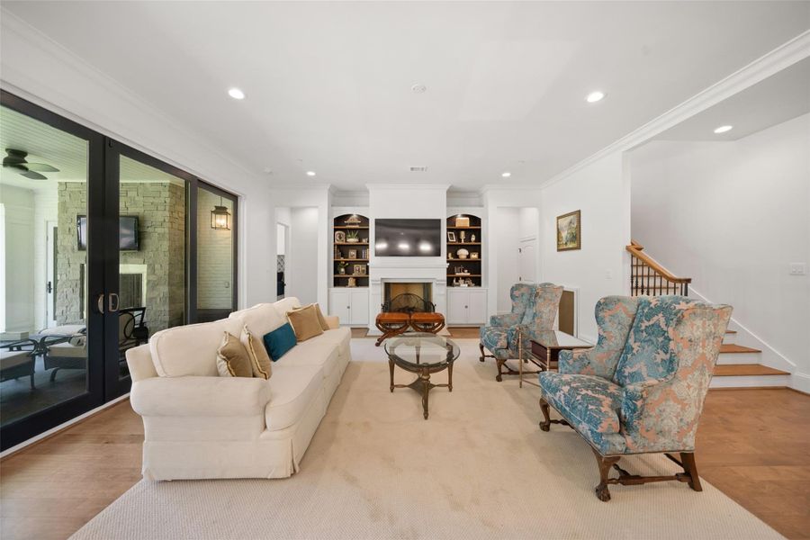 The living room is a bright, airy space with large doors that open to a beautifully manicured backyard and patio.