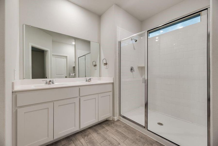 Bathroom featuring a dual vanity with white cabinetry and an integrated countertop