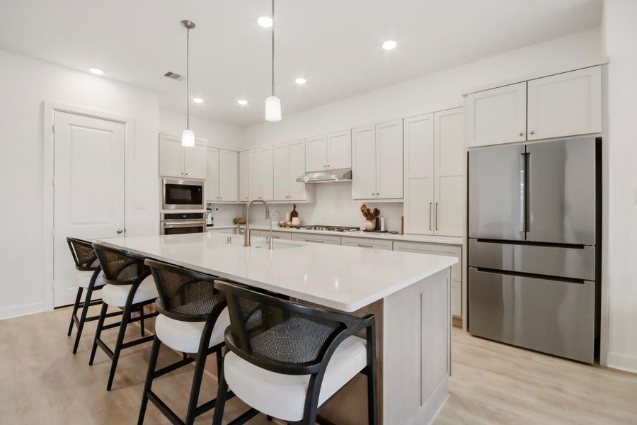 Sleek modern kitchen featuring a large island with seating, stainless steel appliances, and ample cabinetry for storage.