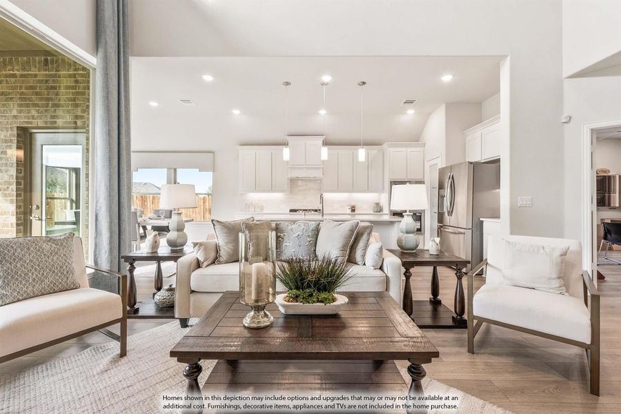 Open-concept living room with wood coffee table and white sofa, open to kitchen with white cabinets and stainless appliances