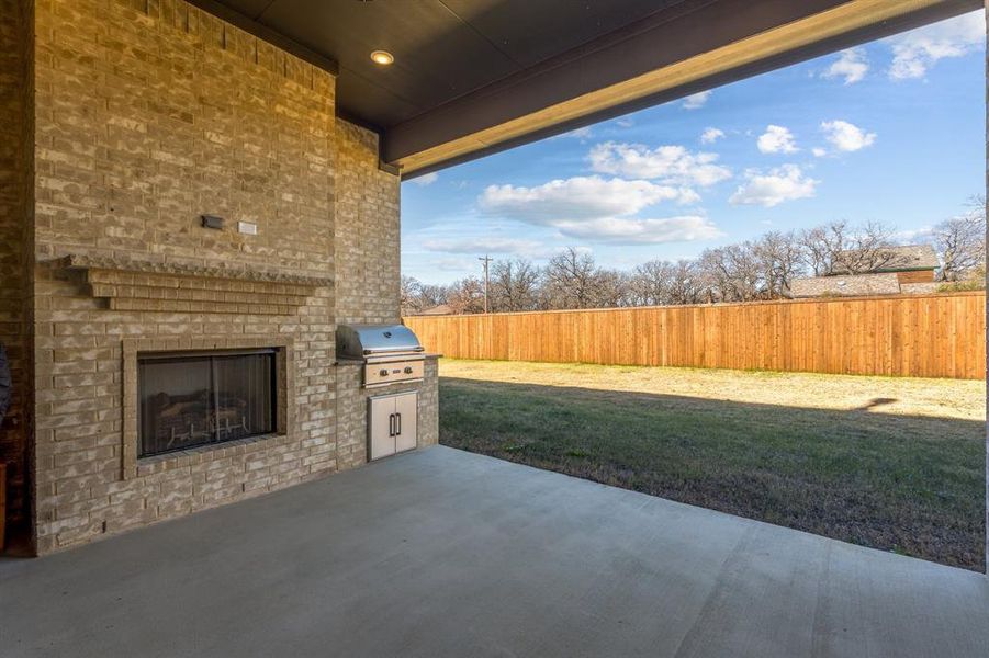 View of patio featuring an outdoor brick fireplace and a grill