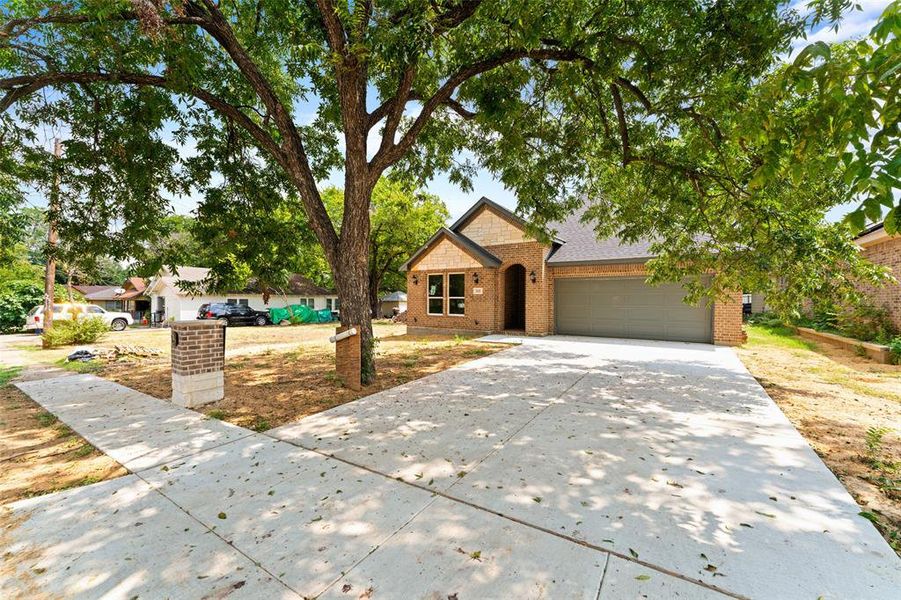 View of front of home with brick siding, concrete driveway, an attached garage, and roof with shingles