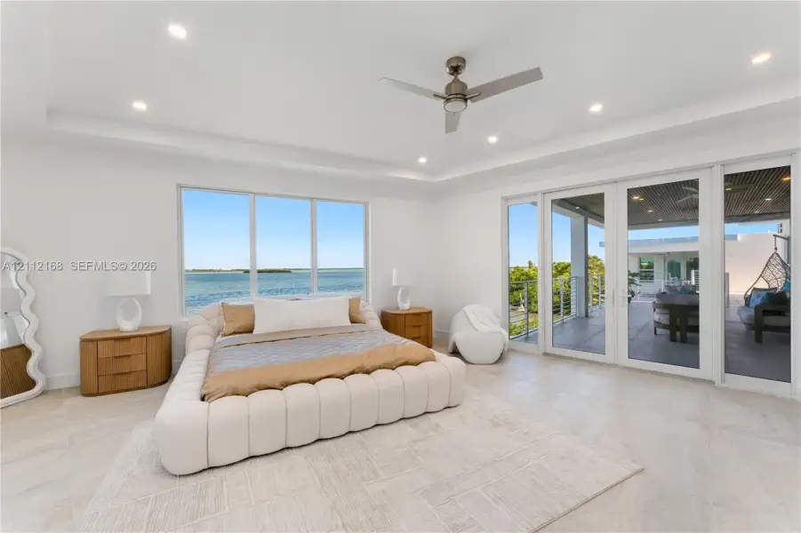 Tray ceiling with recessed lighting, ceiling fan, large windows, and floor-to-ceiling glass panel doors opening to a covered terrace Tray ceiling with recessed lighting, ceiling fan, large windows, and floor-to-ceiling glass panel doors opening to a covered terrace
