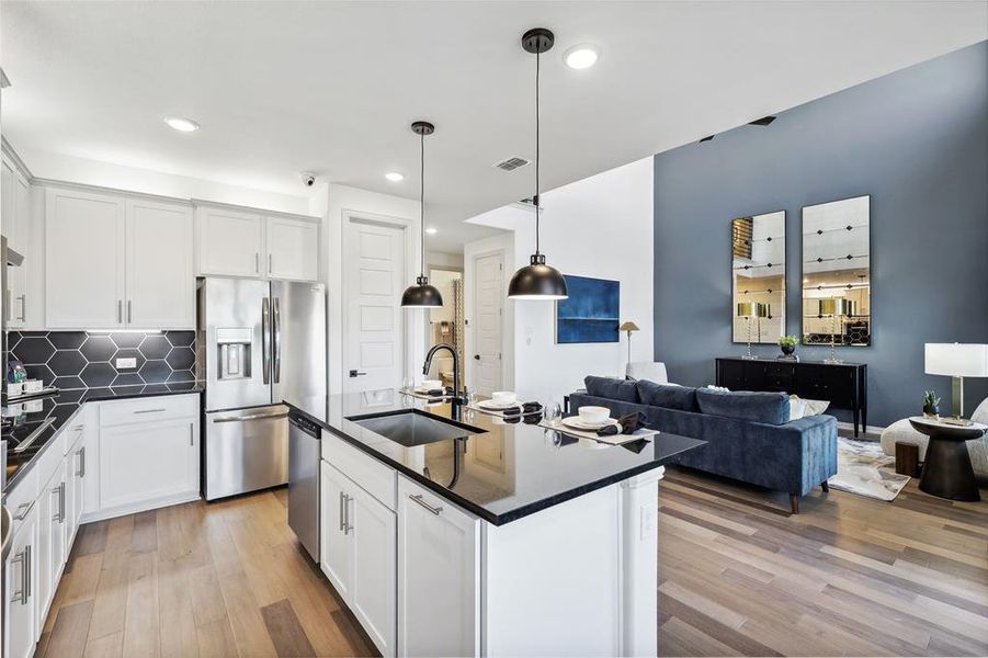 Kitchen featuring white cabinetry, sink, decorative light fixtures, and appliances with stainless steel finishes