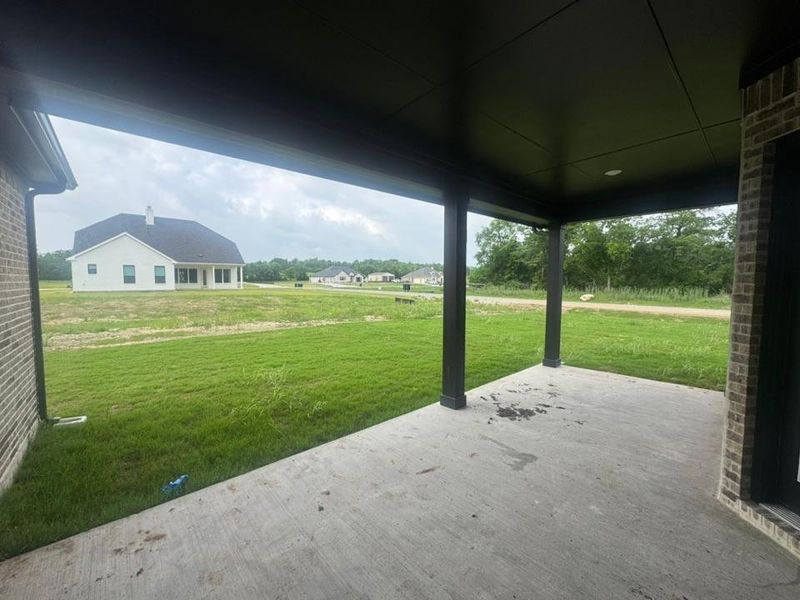 Expansive concrete patio featuring a dark soffit and dark support columns