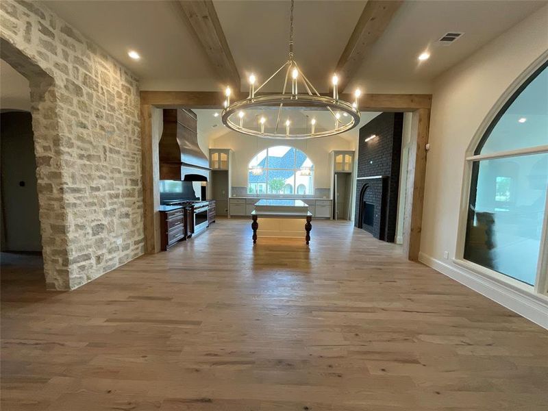 Playroom featuring beam ceiling, wood-type flooring, a chandelier, and a fireplace