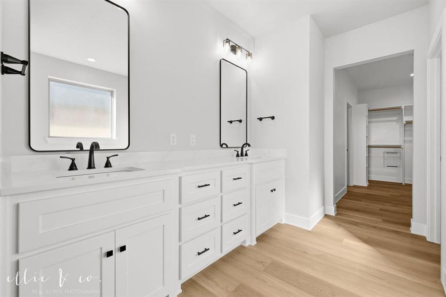 Full bath with a spacious closet, double vanity, light wood-style floors, and recessed lighting