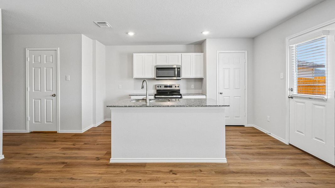 A well-appointed kitchen features a spacious island with a sink and modern stainless steel appliances.