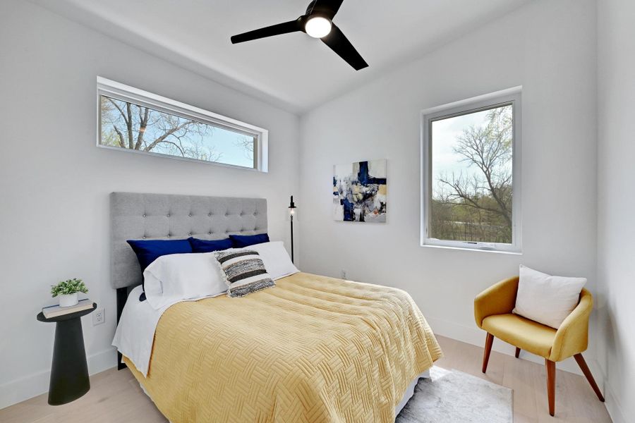 Bedroom featuring vaulted ceiling, baseboards, light wood finished floors, and ceiling fan