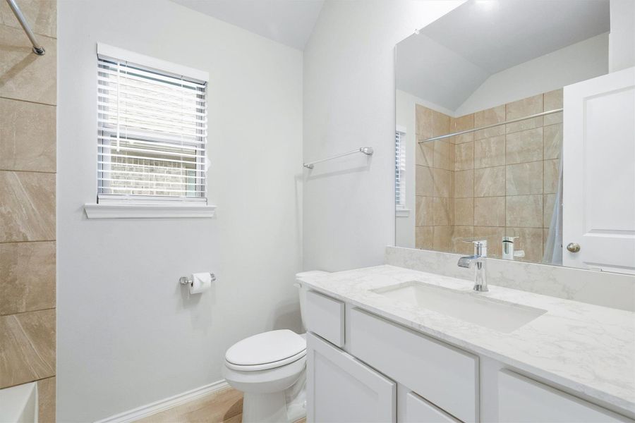 Clean, bright, and well appointed. The secondary bath features a stone countertop vanity, large mirror, vaulted ceiling, and a window for natural light. Guests will feel right at home. Clean, bright, and well appointed. The secondary bath features a stone countertop vanity, large mirror, vaulted ceiling, and a window for natural light. Guests will feel right at home.