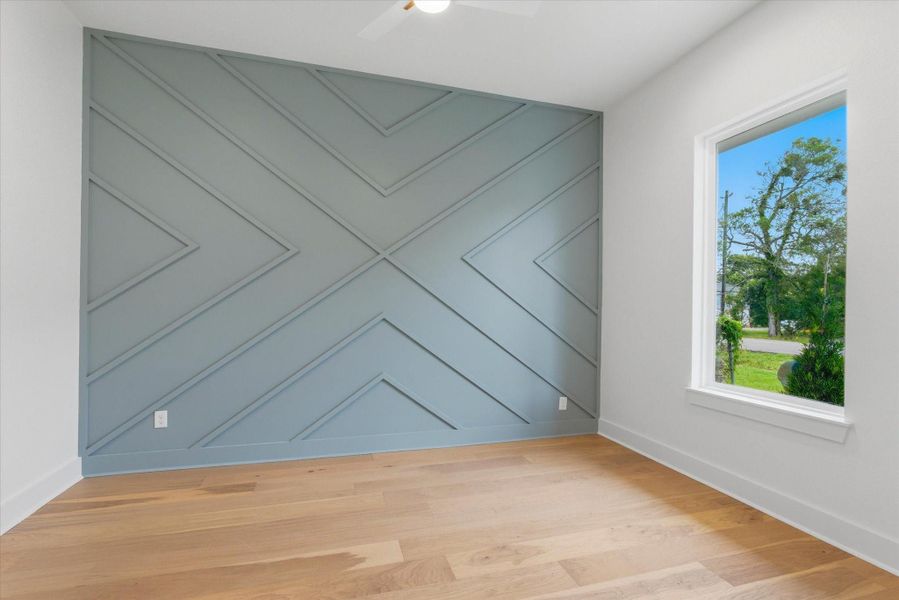 Home office is fully equipped with large picture windows, custom accent wall, and ceiling fan for added comfort.