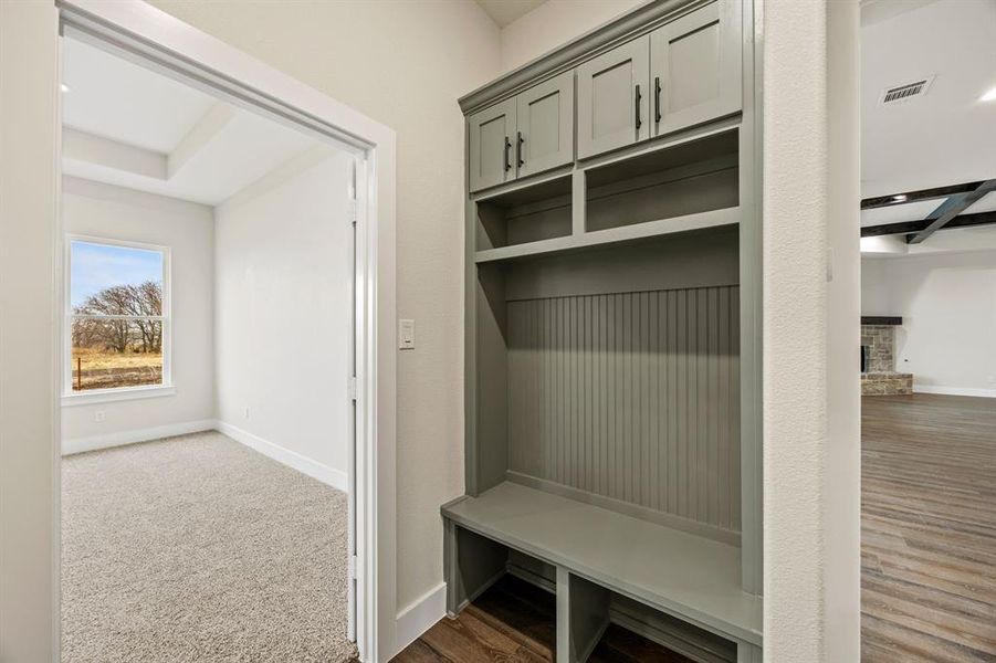 Mudroom featuring dark wood-type flooring and a brick fireplace Mudroom featuring dark wood-type flooring and a brick fireplace