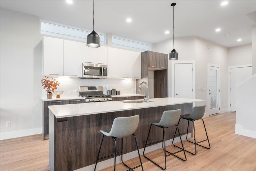 The oversized island comfortably seats four, illuminated by custom pendant lighting that adds a warm, modern touch to the heart of the home. The oversized island comfortably seats four, illuminated by custom pendant lighting that adds a warm, modern touch to the heart of the home.