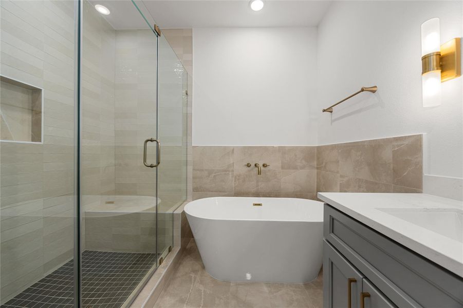 This additional view of the primary bath showcases a walk-in shower with tile surround and a separate garden tub perfect for soaking after a long day. This additional view of the primary bath showcases a walk-in shower with tile surround and a separate garden tub perfect for soaking after a long day.