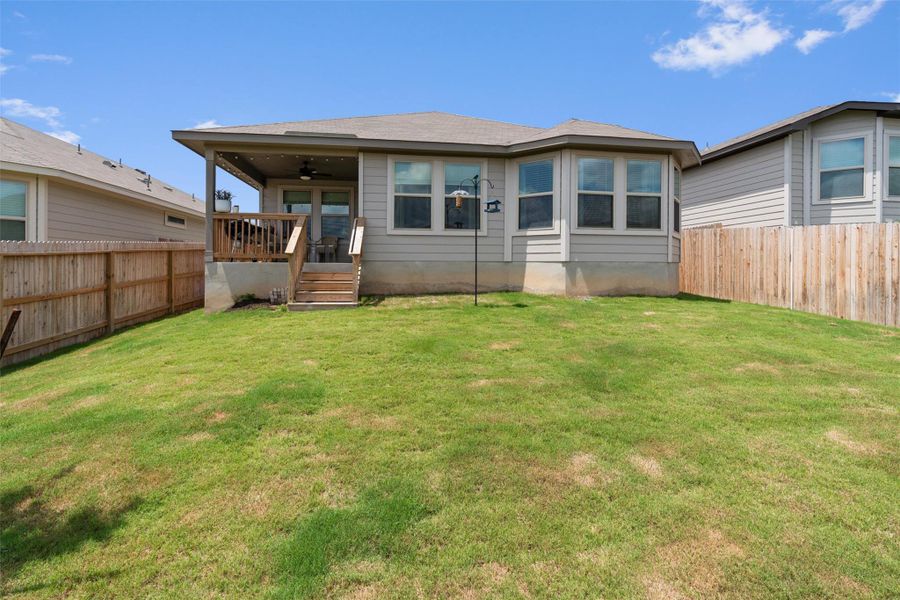 Expansive backyard featuring a covered patio, wood fencing, a tiered wood deck, and an exterior with multiple windows Expansive backyard featuring a covered patio, wood fencing, a tiered wood deck, and an exterior with multiple windows