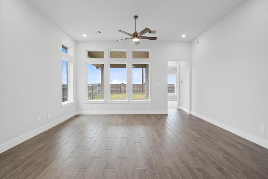 A grand great room with tall ceilings, ceiling fan, abundant natural light, and an open, inviting ambiance--perfect for gatherings, relaxation, and making memories.