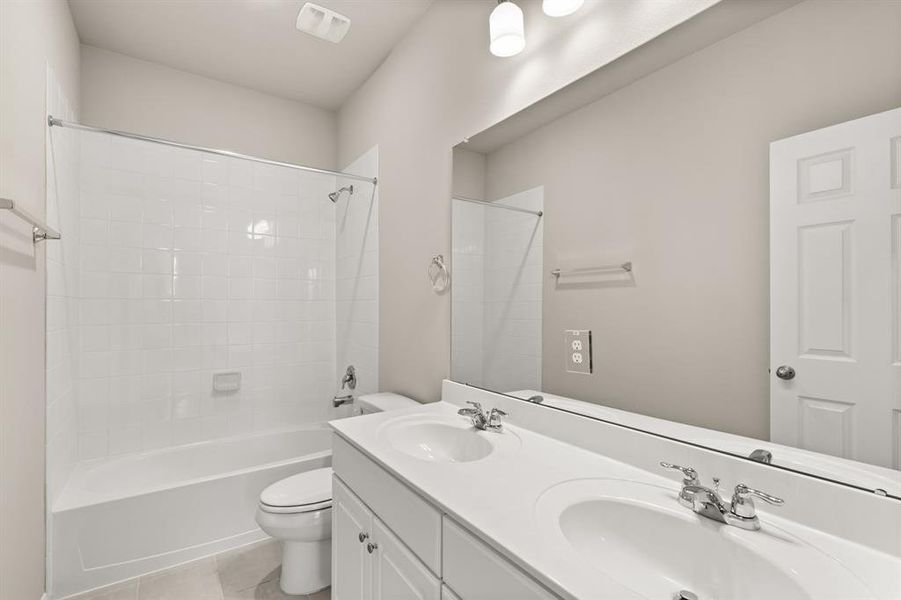 The secondary bath features tile flooring, white cabinetry and light countertops and a shower/tub combo. Perfect for accommodating any visiting family and friends.