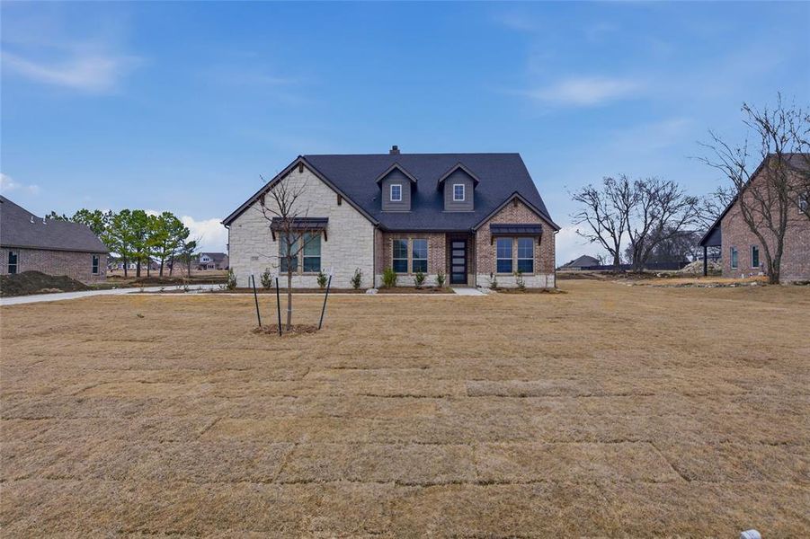 View of front of house featuring a front yard, stone siding, and a chimney