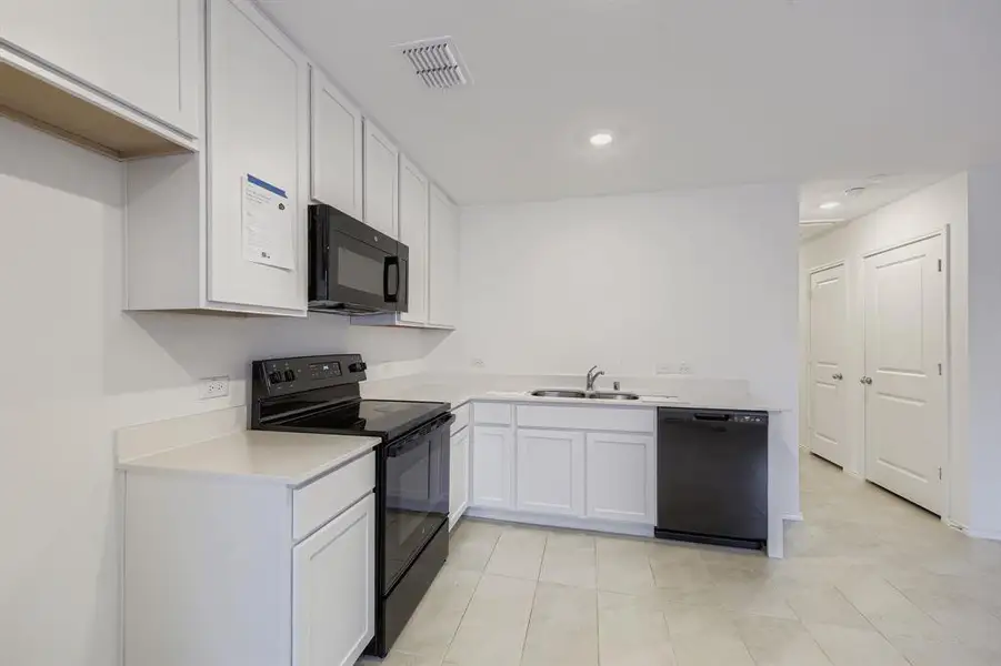 Kitchen featuring light countertops, white cabinets, black appliances, recessed lighting, and open floor plan