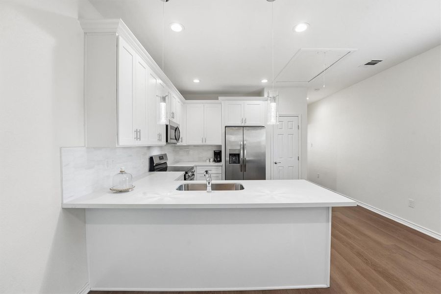 The kitchen takes center stage with expansive quartz countertops, a generous island, and tall cabinetry that maximize storage and functionality while maintaining a clean, modern aesthetic.