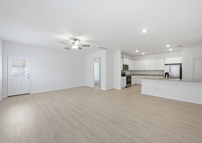Open-concept family room featuring a ceiling fan, wood-look vinyl flooring, and a sightline into the kitchen. Open-concept family room featuring a ceiling fan, wood-look vinyl flooring, and a sightline into the kitchen.