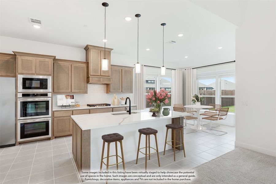 Kitchen with tan wood cabinets, white quartz island, double ovens, and pendant lights open to dining area