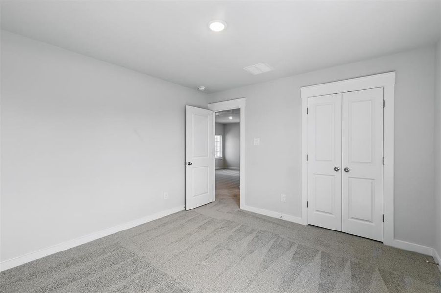 Unfurnished bedroom with light carpet, a closet, and recessed lighting