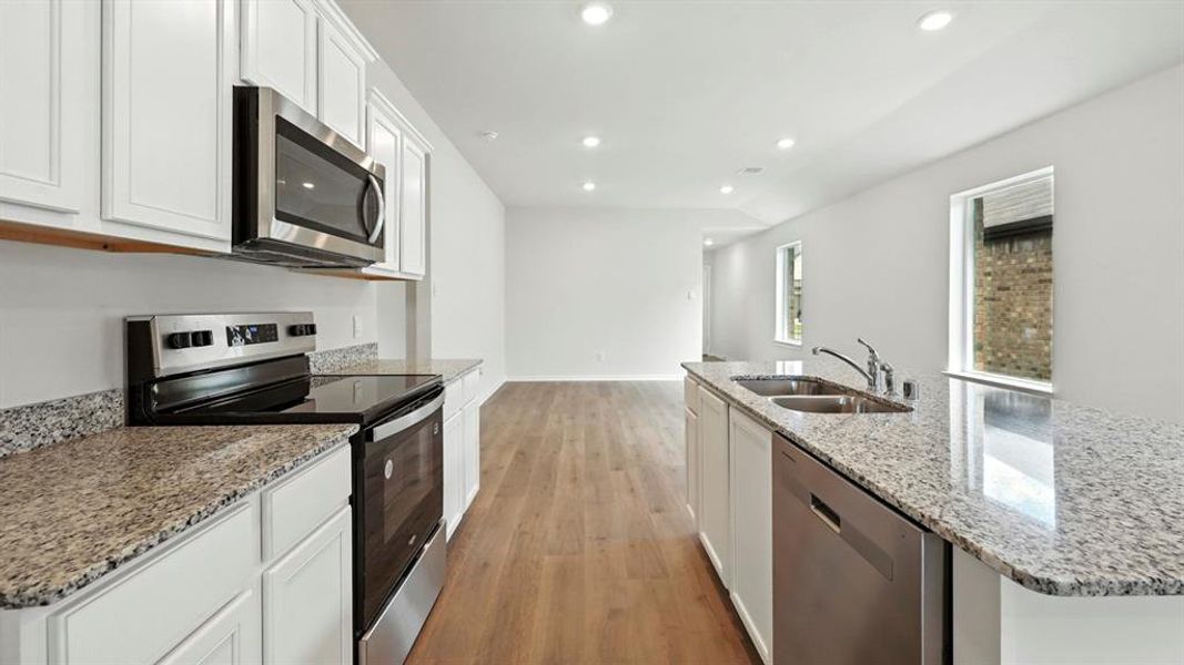 Modern kitchen featuring light-toned cabinetry and granite countertops Modern kitchen featuring light-toned cabinetry and granite countertops