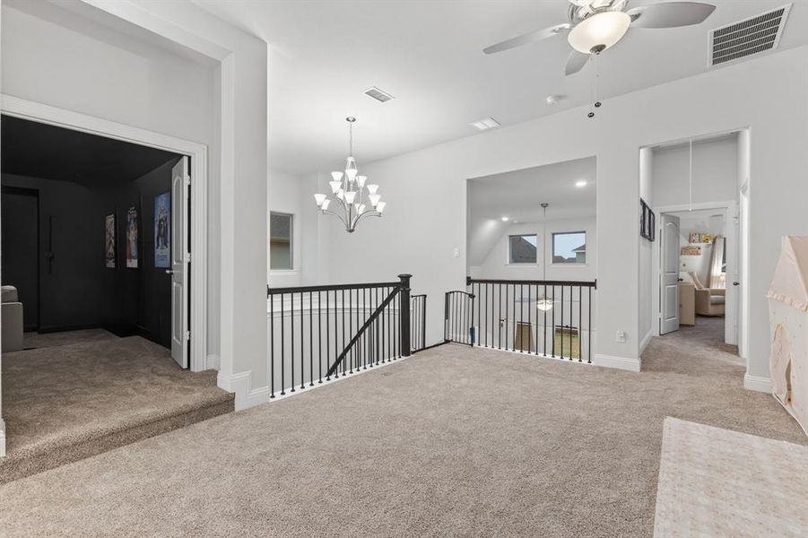 Carpeted spare room with ceiling fan and a chandelier Carpeted spare room with ceiling fan and a chandelier