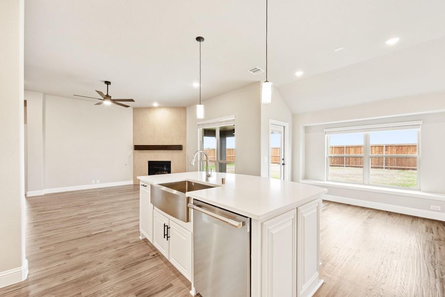 Kitchen island with farmhouse sink and stainless dishwasher, open to living room with fireplace and hardwood floors Kitchen island with farmhouse sink and stainless dishwasher, open to living room with fireplace and hardwood floors