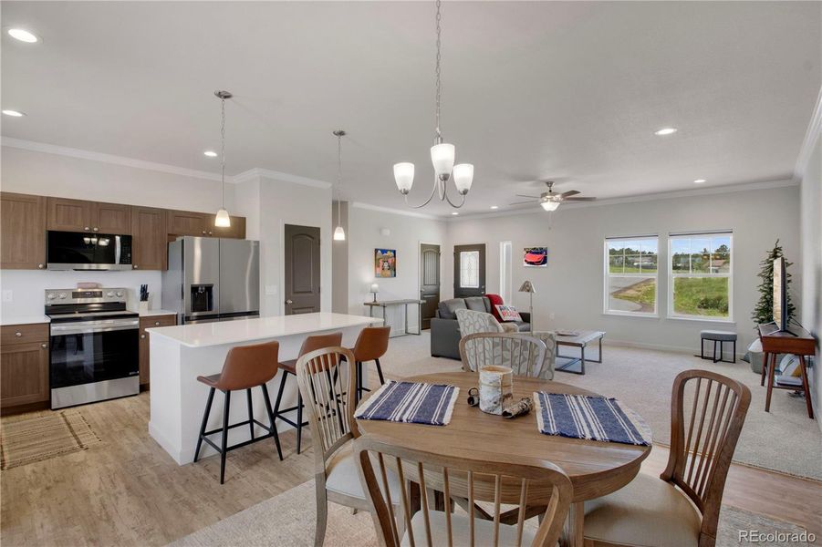 Kitchen featuring appliances with stainless steel finishes, light wood-style flooring, crown molding, a kitchen breakfast bar, and a center island