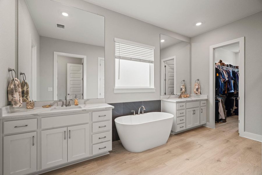 Bathroom featuring a freestanding tub, two vanities, light wood finished floors, a walk in closet, and recessed lighting Bathroom featuring a freestanding tub, two vanities, light wood finished floors, a walk in closet, and recessed lighting