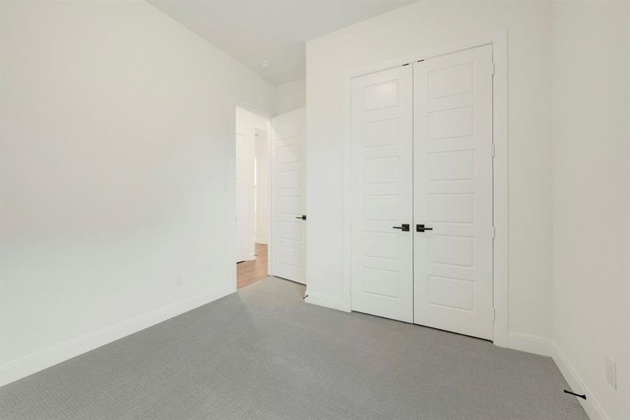Unfurnished bedroom with carpet flooring and a closet Unfurnished bedroom with carpet flooring and a closet