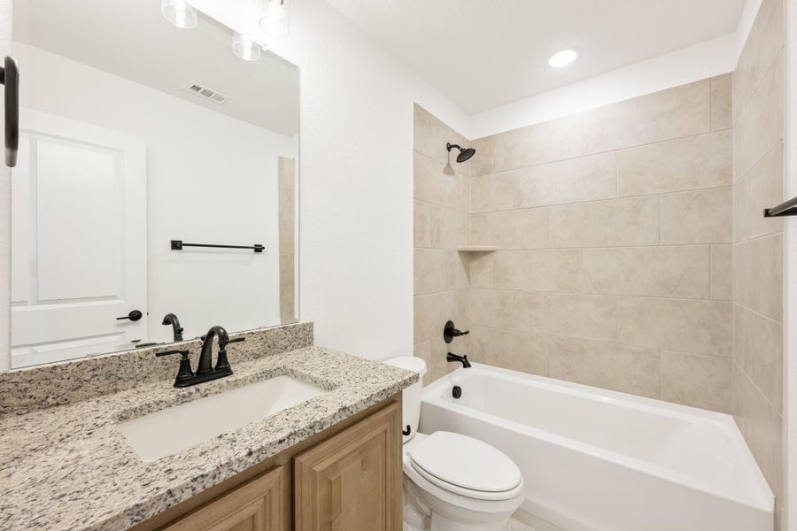 Bathroom with granite countertop vanity, tub-shower combo with beige tile surround, and dark bronze fixtures Bathroom with granite countertop vanity, tub-shower combo with beige tile surround, and dark bronze fixtures