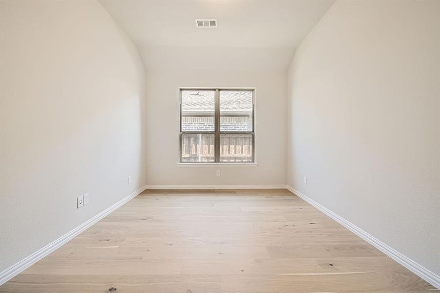 Empty room with lofted ceiling and light hardwood / wood-style floors