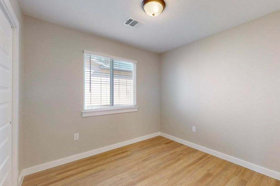Spare room with visible vents, baseboards, and light wood finished floors