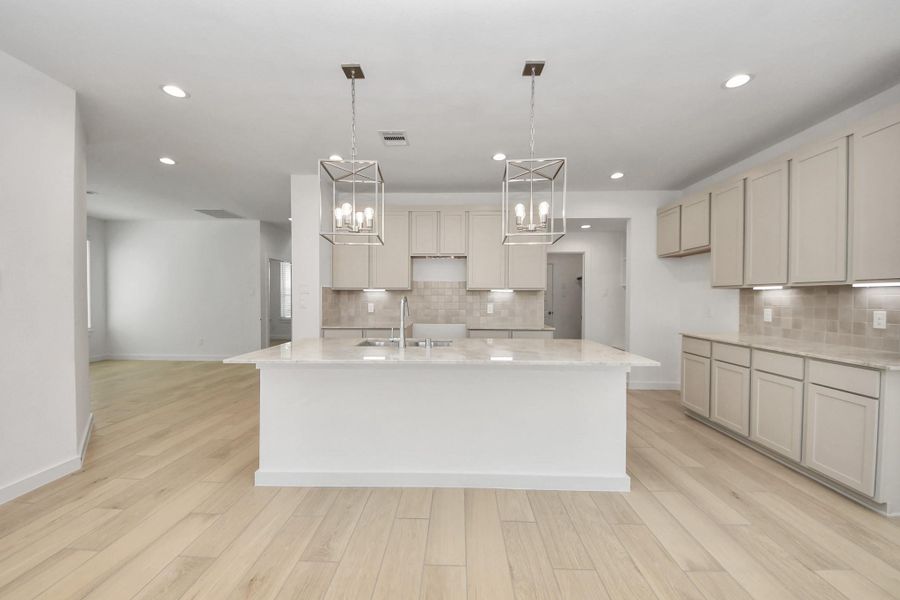 The kitchen is a culinary haven, featuring granite countertops, a tile backsplash, stainless steel appliances, 42” upper cabinets, and undercabinet lighting. Sample photo of completed home with similar floor plan. Actual colors and selections may vary.