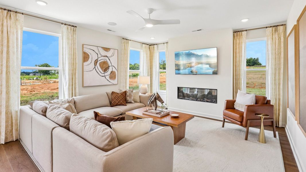 Gathering room with ceiling fan, hard surface flooring, fireplace, and natural lighting from windows Gathering room with ceiling fan, hard surface flooring, fireplace, and natural lighting from windows