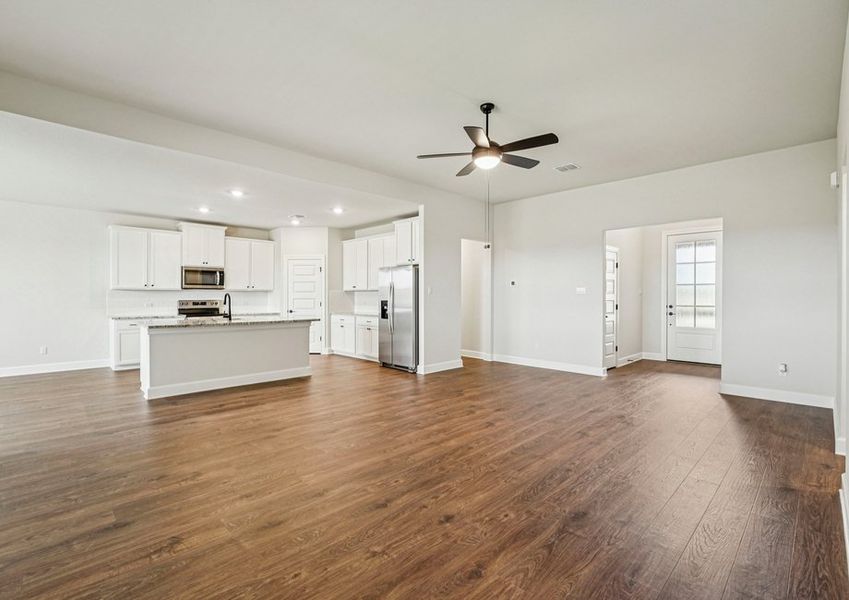 Kitchen featuring a granite island, white cabinetry, and stainless steel appliances with wood-look vinyl flooring. Kitchen featuring a granite island, white cabinetry, and stainless steel appliances with wood-look vinyl flooring.