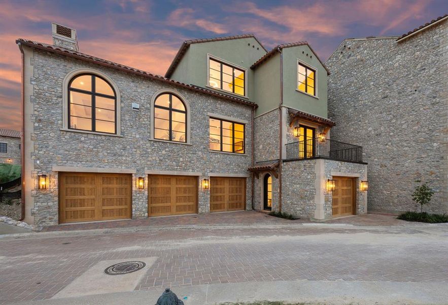 Mediterranean / spanish house with a balcony, stone siding, a garage, decorative driveway, and a chimney Mediterranean / spanish house with a balcony, stone siding, a garage, decorative driveway, and a chimney