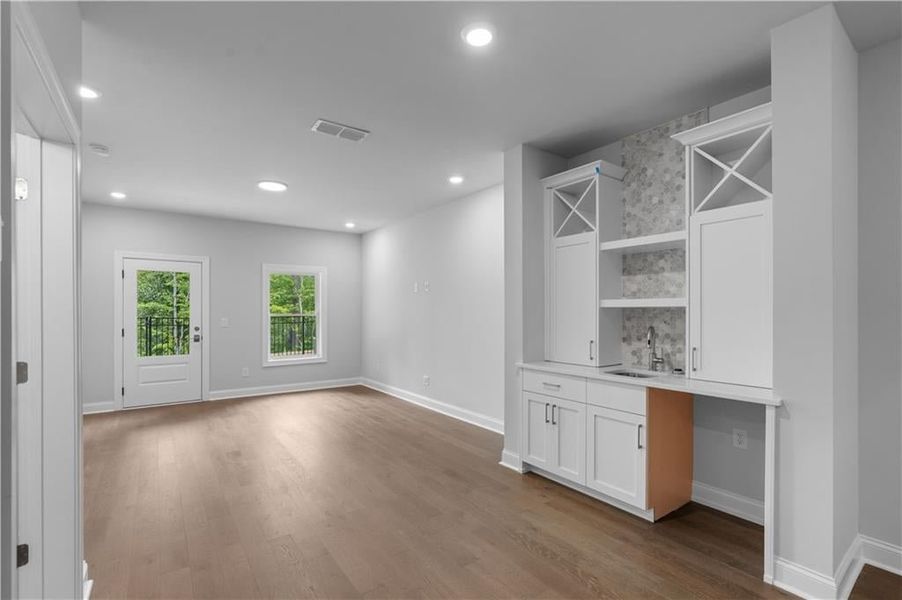 Indoor wet bar featuring white cabinetry, open shelves, light wood-style floors, and recessed lighting Indoor wet bar featuring white cabinetry, open shelves, light wood-style floors, and recessed lighting