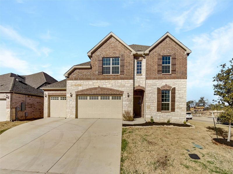 View of front of property featuring brick siding, an attached garage, concrete driveway, and a shingled roof