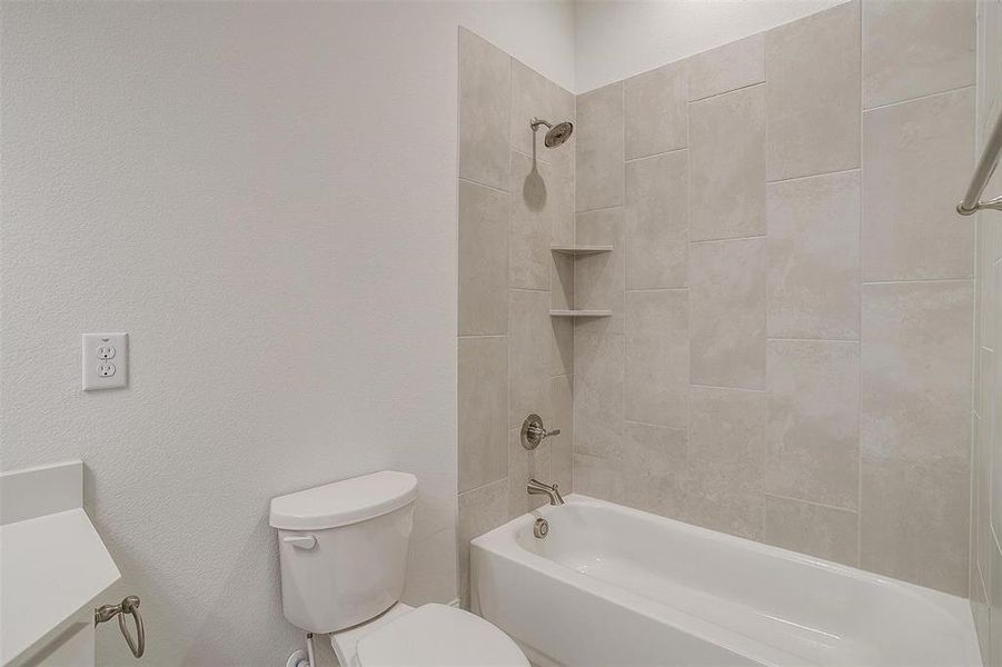 Bathroom featuring tiled shower / bath combo and toilet